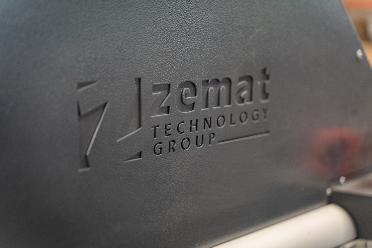 Logo Zemat Technology Group na czarnej obudowie maszyny.