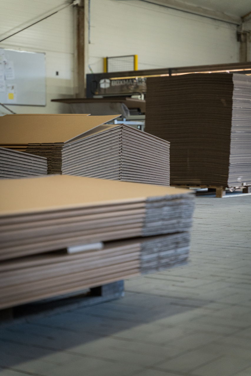 Pionowe ujęcie stosów palet z tekturą w hali produkcyjnej.